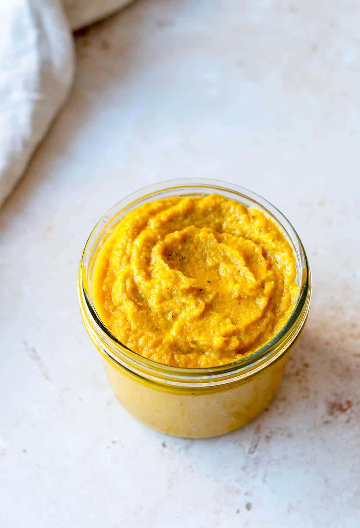 Concentrated vegetable stock paste in a glass jar on a stone benchtop.