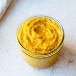 Homemade vegetable stock paste in a glass jar on a light background.