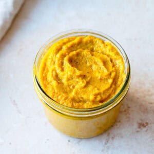 Homemade vegetable stock paste in a glass jar on a light background.