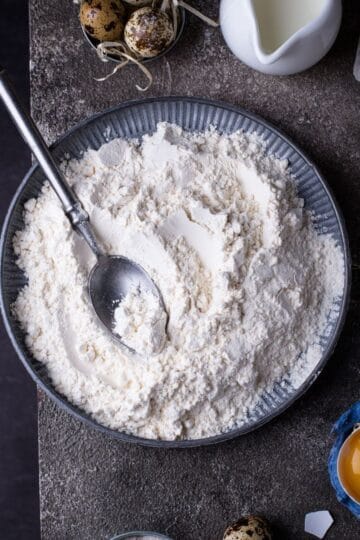 A bowl of flour on a dark background.