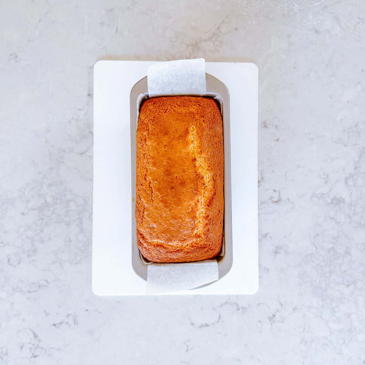 A baked cake in a rectangle shaped baking tin.