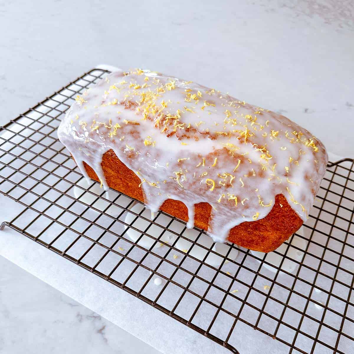 An iced cake sitting on a baking rack.