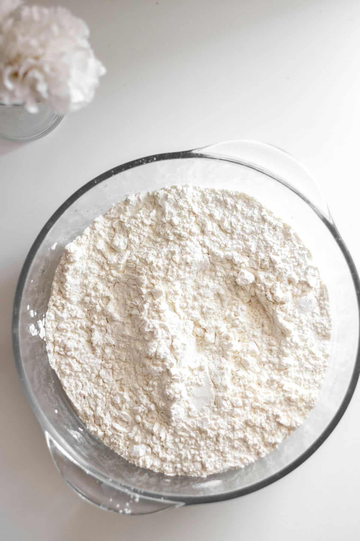 A glass bowl filled with white flour.